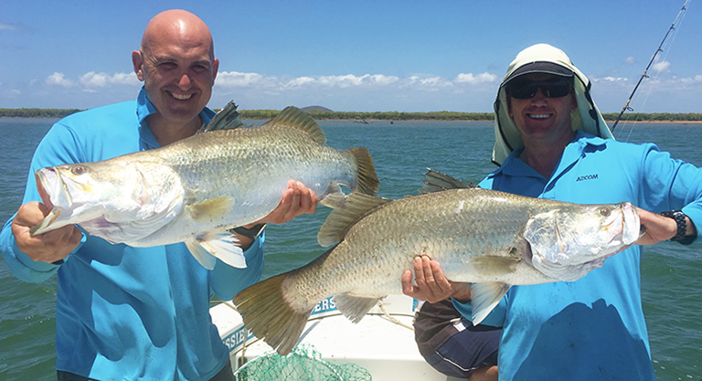 Two men holding barramundi in boat charter townsville